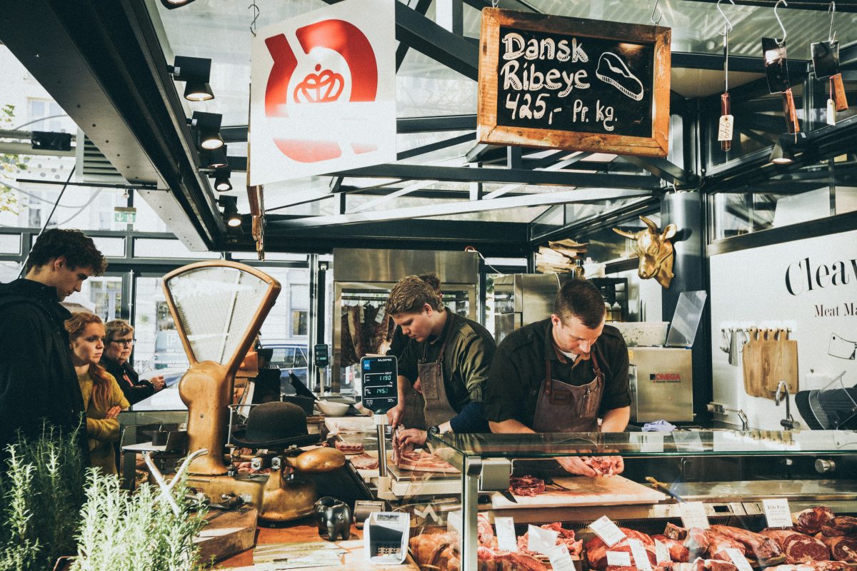 A group of butchers at a meatshop prepares an order for a customer. Photo by Nick Karvounis on Unsplash.